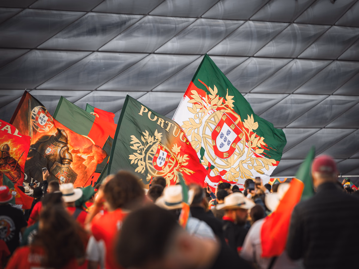 A large crowd of supporters waving national flags outside a football stadium