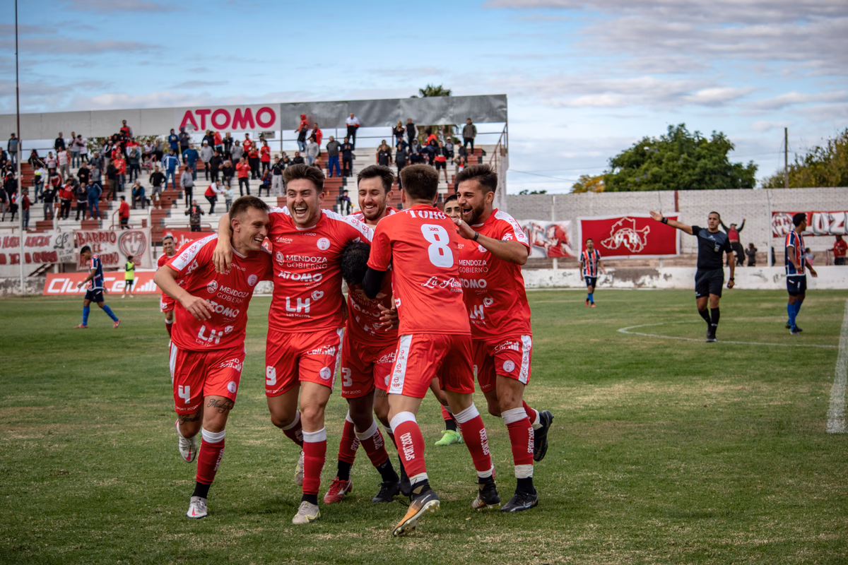 A group of players in red running to celebrate a goal together